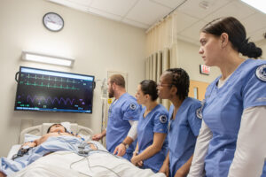 Students looking at vitals of a mankin in a simulation center